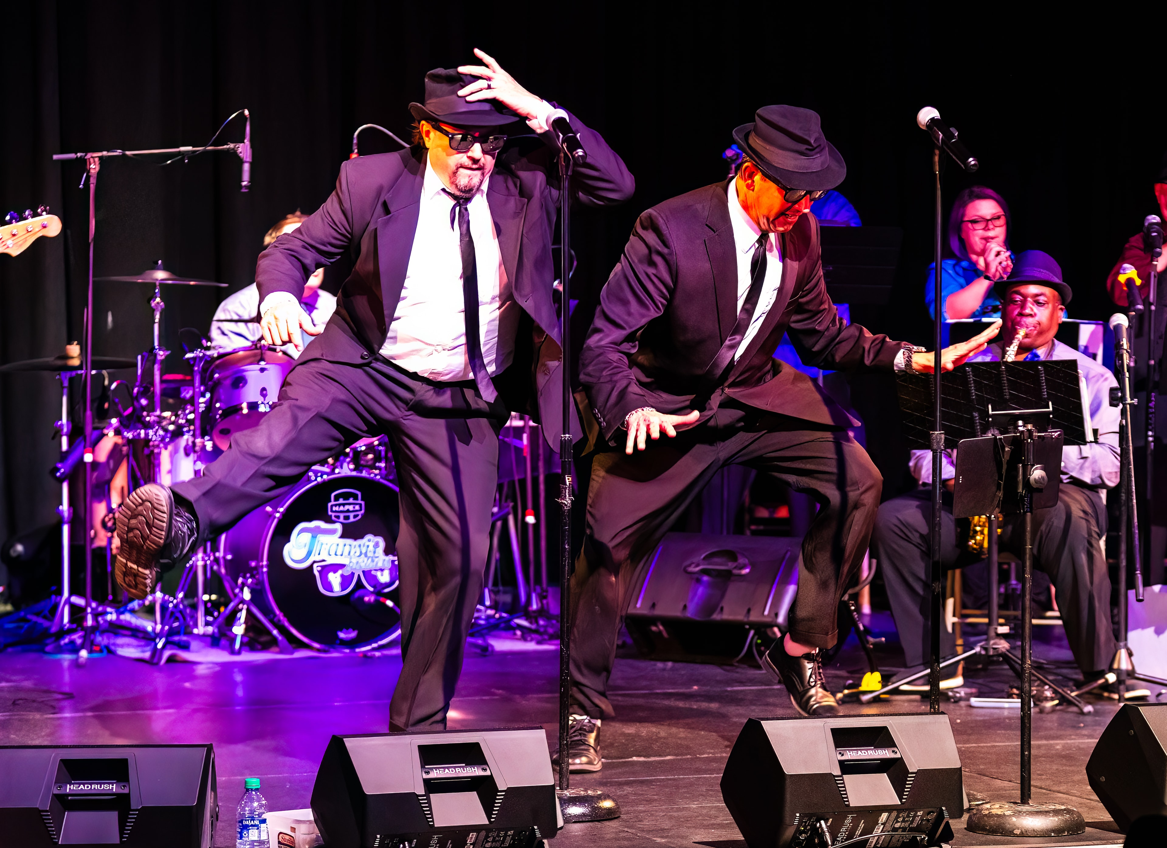 Jake and Elwood performing on stage with the full Transit Brothers Blues Brothers live band behind them