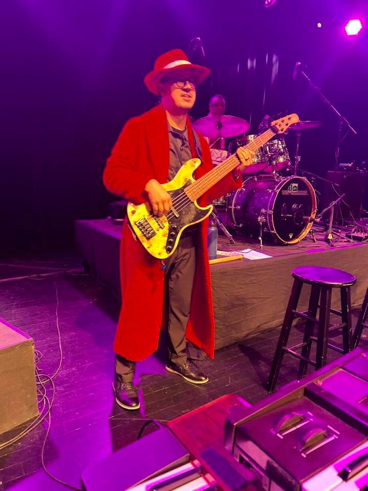 Transit Brothers bassist in red performing on stage with drummer behind